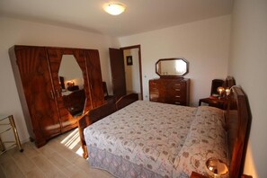 A bedroom with a bed, a wardrobe, a dresser, and a mirror.