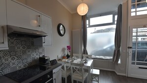 A modern kitchen with white cabinets, a patterned backsplash, and a dining area with a table set for four.