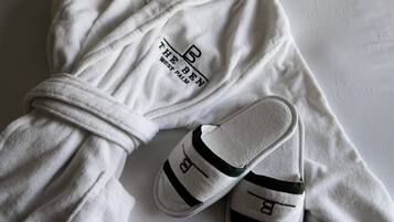 Une paire de pantoufles blanches, ornées d’un logo et d’une inscription sur la semelle, posée sur une surface blanche.