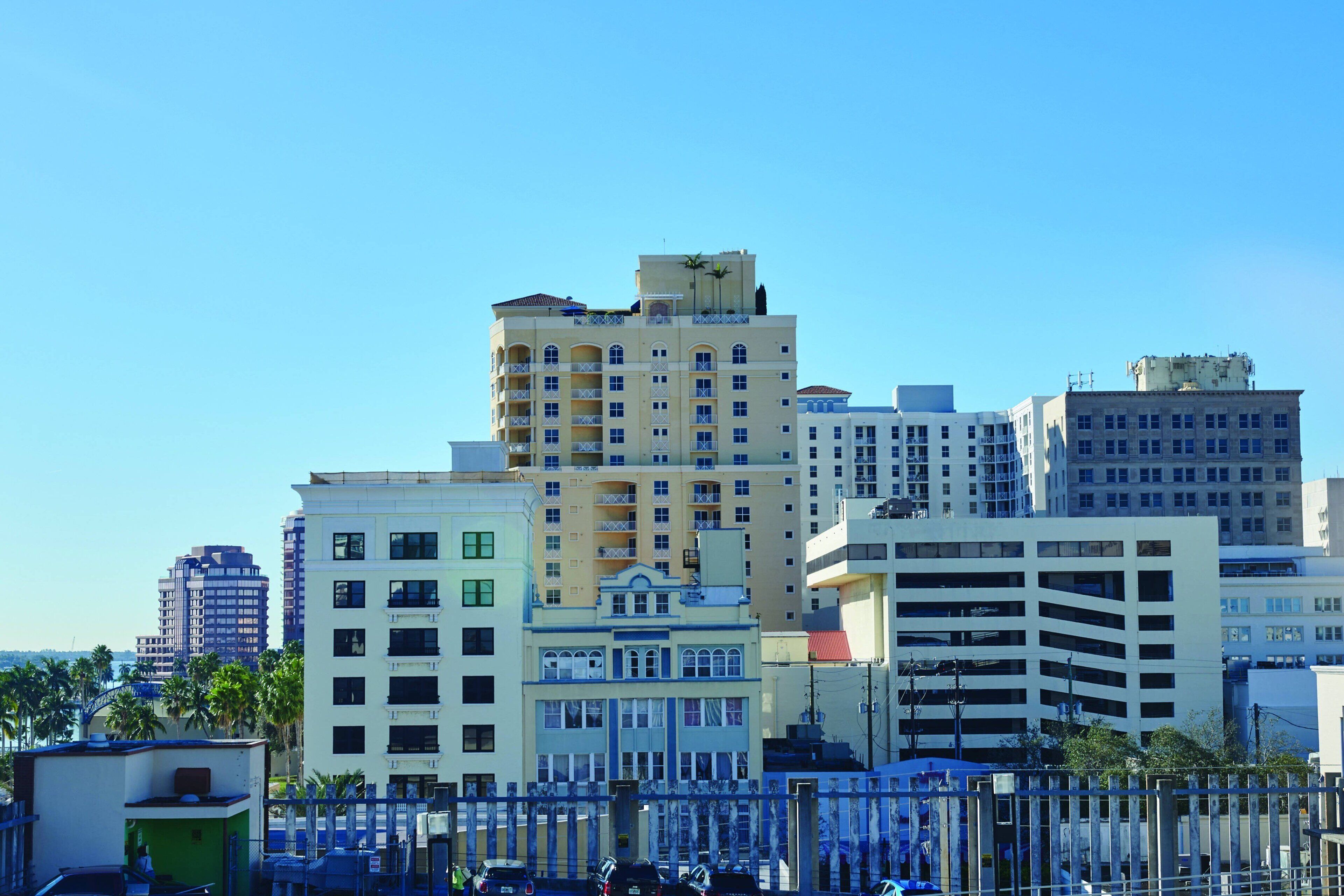 Un hôtel à plusieurs étages doté de balcons, d’un parking et surplombant un ciel d’un bleu limpide.