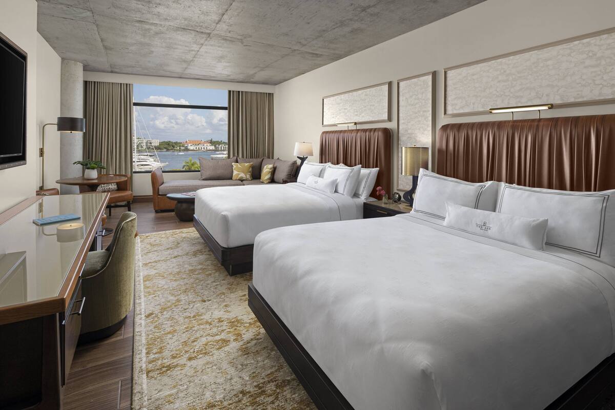 Een moderne hotelkamer met twee bedden, een bureau en uitzicht op het water.