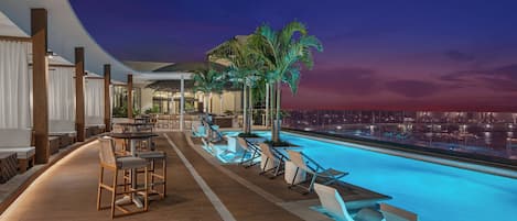 Una piscina al aire libre, sombrillas, sillones reclinables de piscina