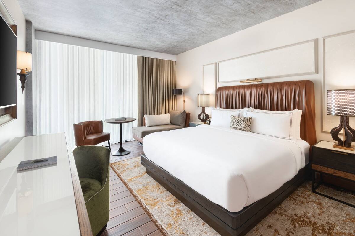Een moderne hotelkamer met een groot bed, een bureau, een stoel en een klein tafeltje.