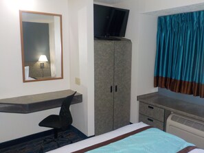 Relax in a cozy space with a comfortable bed, desk, and TV.