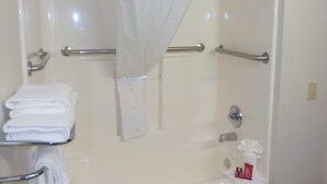 Un baño con ducha, toallero y barras de apoyo.