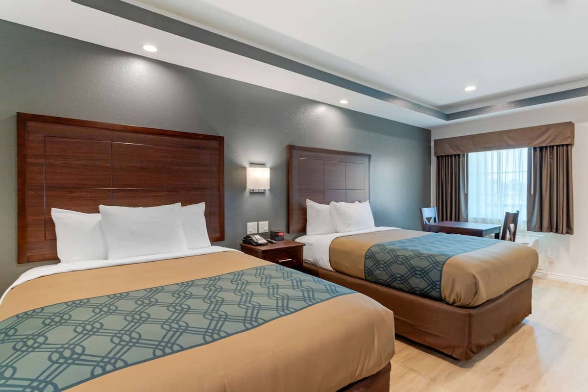 A hotel room with two beds, a desk, and a chair.