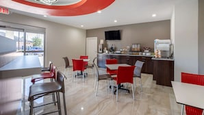 A modern restaurant with a bar area, red and grey chairs, and a kitchen in the background. - Econo Lodge Houston Northwest - Cypress (Houston)
