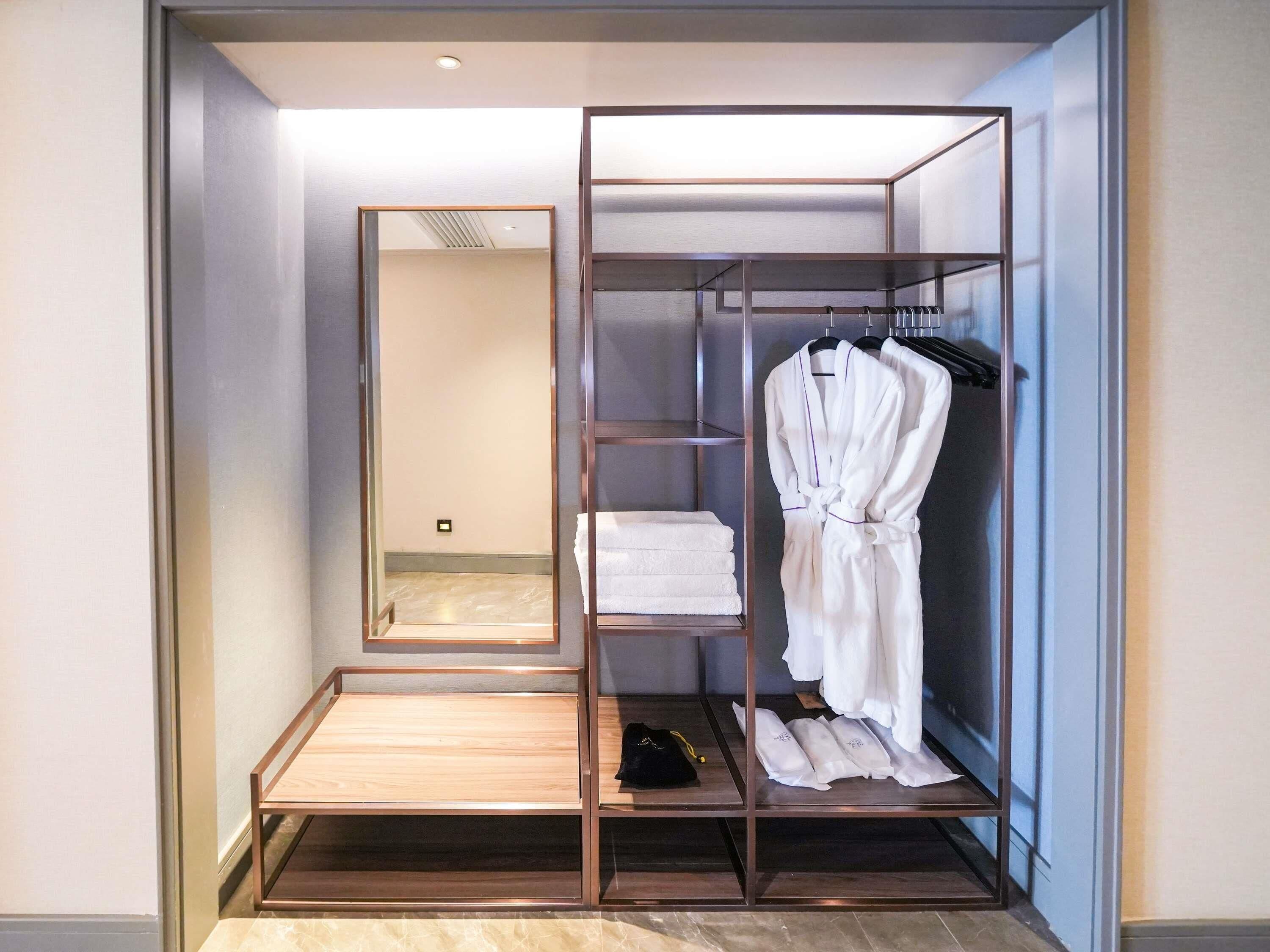 Um closet espaçoso com armário espelhado, prateleiras e cabideiro.