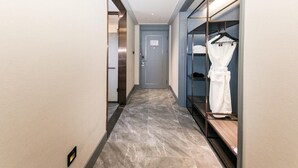 A hallway with a marble floor, a blue door, and a clothing rack with a white robe. - Mercure Xian Qujiang (Xi'an)