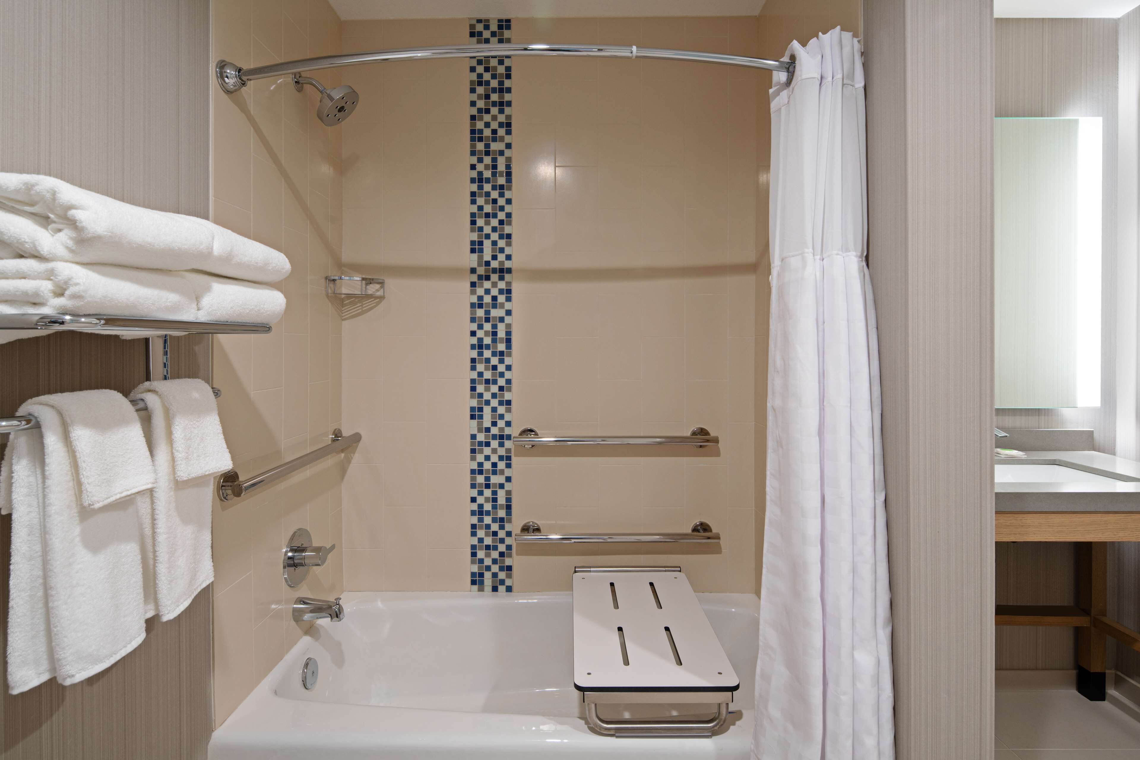 A modern bathroom with a shower, a bathtub, and a toilet. There are towels hanging on a rack, and a mirror above the sink.