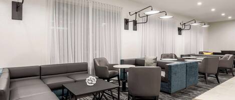 Een moderne hotel lobby met een hoekbank, een kleine tafel en een blauw accent.