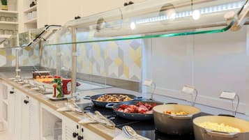 A buffet area with various food options, including salads, meats, and grains, arranged on a counter with a glass partition.