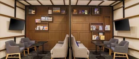 A hotel lobby with a reception desk, two sofas, and a bookshelf with framed pictures and books.
