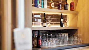 Área de bar com prateleiras cheias de garrafas de bebidas e copos.