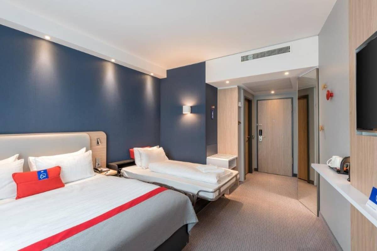 Une chambre d’hôtel avec un grand lit, une table de chevet, un bureau et une télévision.