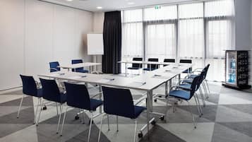 Un salón de conferencias con una pizarra, varias mesas y sillas.