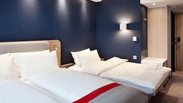 A hotel room with two beds, a wooden headboard, a wall-mounted light, and a wooden door.