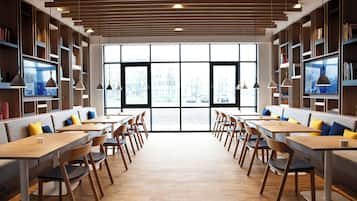 Una biblioteca moderna con estanterías, mesas y sillas dispuestas para leer y comer.