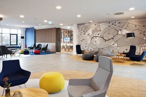 A modern lounge area with seating, a map wall, and a television screen. - Holiday Inn Express Kaiserslautern by IHG (Kaiserslautern)