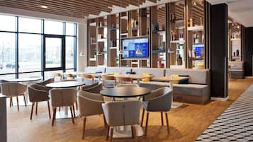 Eine moderne Bibliothek mit Bücherregalen, einem Fernseher und Sitzbereichen.