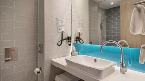 A modern bathroom with a white sink, a blue accent wall, and a mirror.