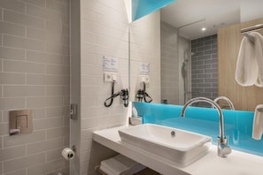 Een moderne badkamer met een wit wastafelmeubel, een blauwe accentmuur en een spiegel.