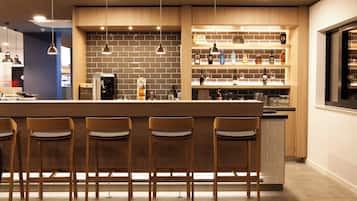 Un área de bar moderna con taburetes de madera, una pared de ladrillo y estantes con botellas.