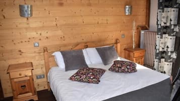 Un dormitorio con paneles de madera, una cama, dos mesitas de noche y un radiador.