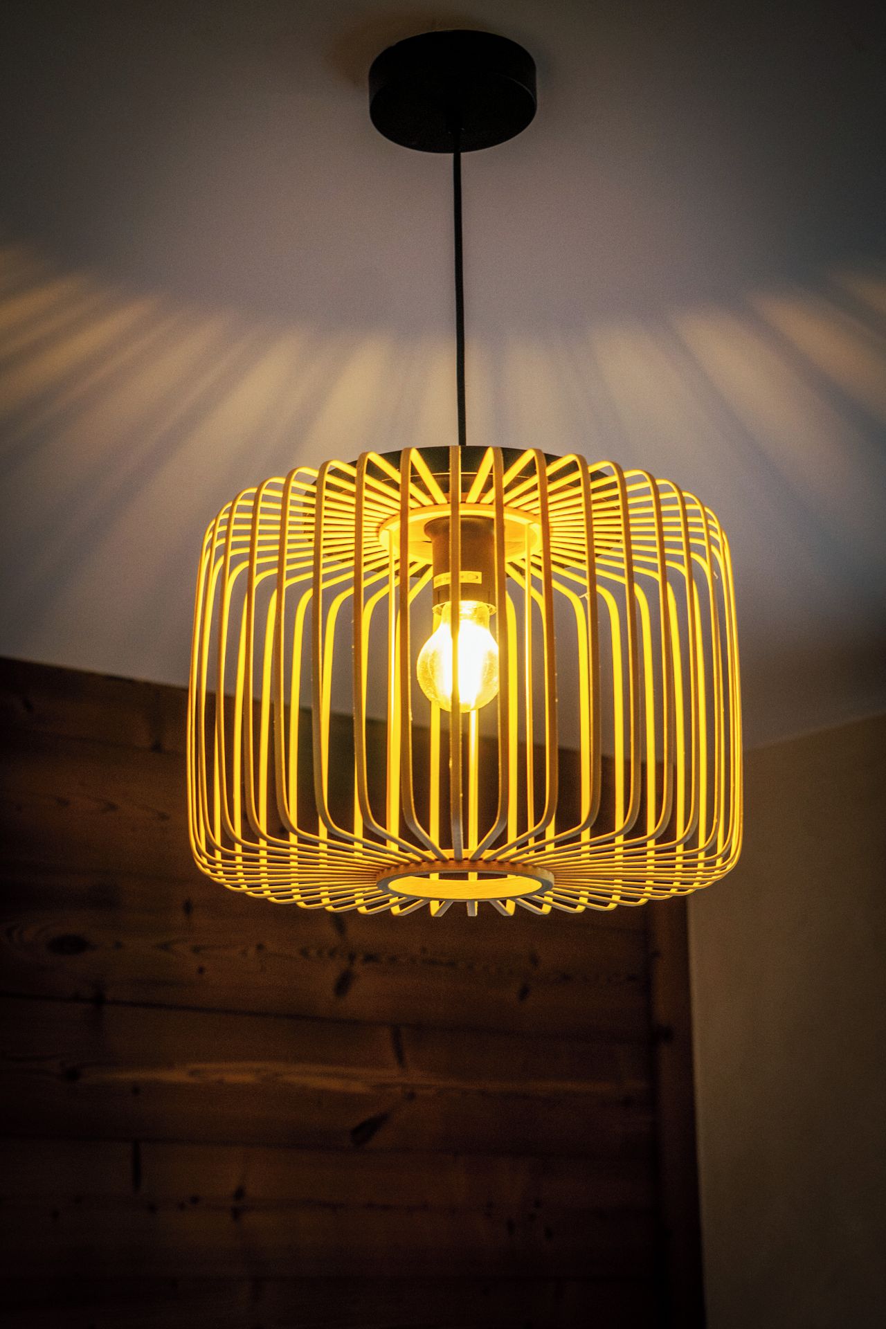 A pendant light fixture with a cylindrical shape and a pattern of vertical lines.