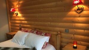 Una habitación con paneles de madera, una cama, dos mesitas de noche y lámparas fijadas a la pared.