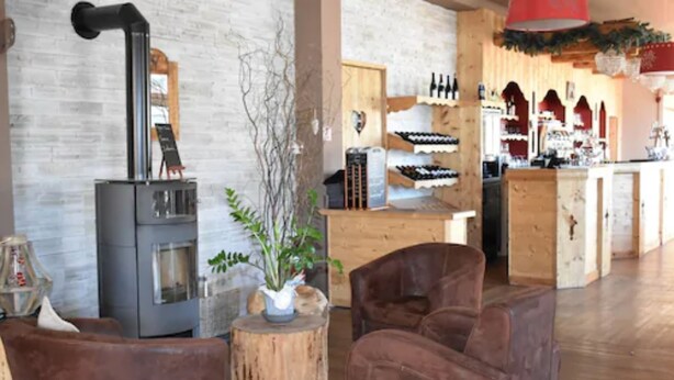 Un ambiente acogedor con una estufa de leña, sillones de cuero y una vitrina para vinos.