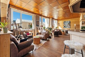 Amplia sala de estar con piso de madera, sofás de cuero y un gran ventanal con vistas al exterior.