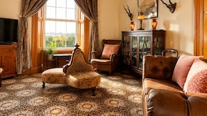 A traditional living room with a sofa, ottoman, and a television. - Nore View House (Dunbell)