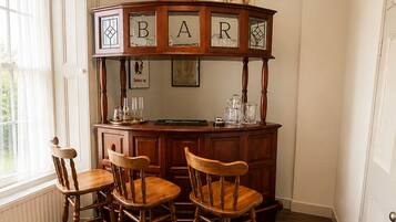 A bar area with wooden chairs, a bar counter, and a hanging light fixture.