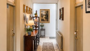 A hallway with a chandelier, framed artwork, a desk with a lamp, and a rug. - Nore View House (Dunbell)