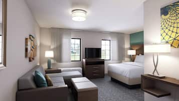 A hotel room with a sofa, a bed, a TV, and a desk.