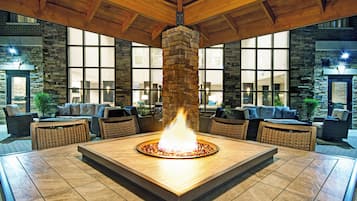 A lobby with a central fire feature, stone walls, and large windows.
