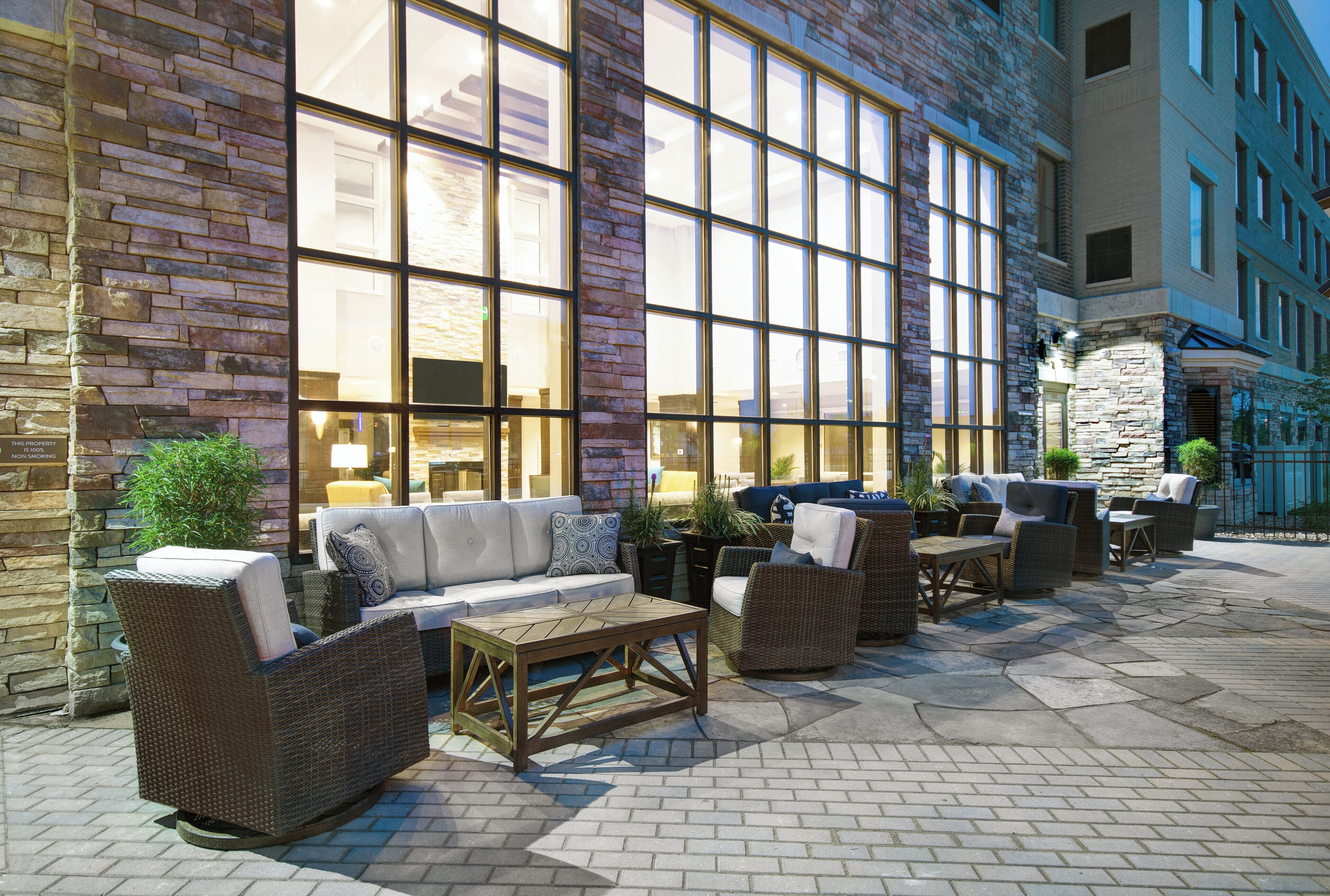 An outdoor seating area with wicker furniture and a stone wall.