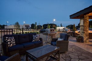 An outdoor patio area with a sofa, chairs, and a grill.