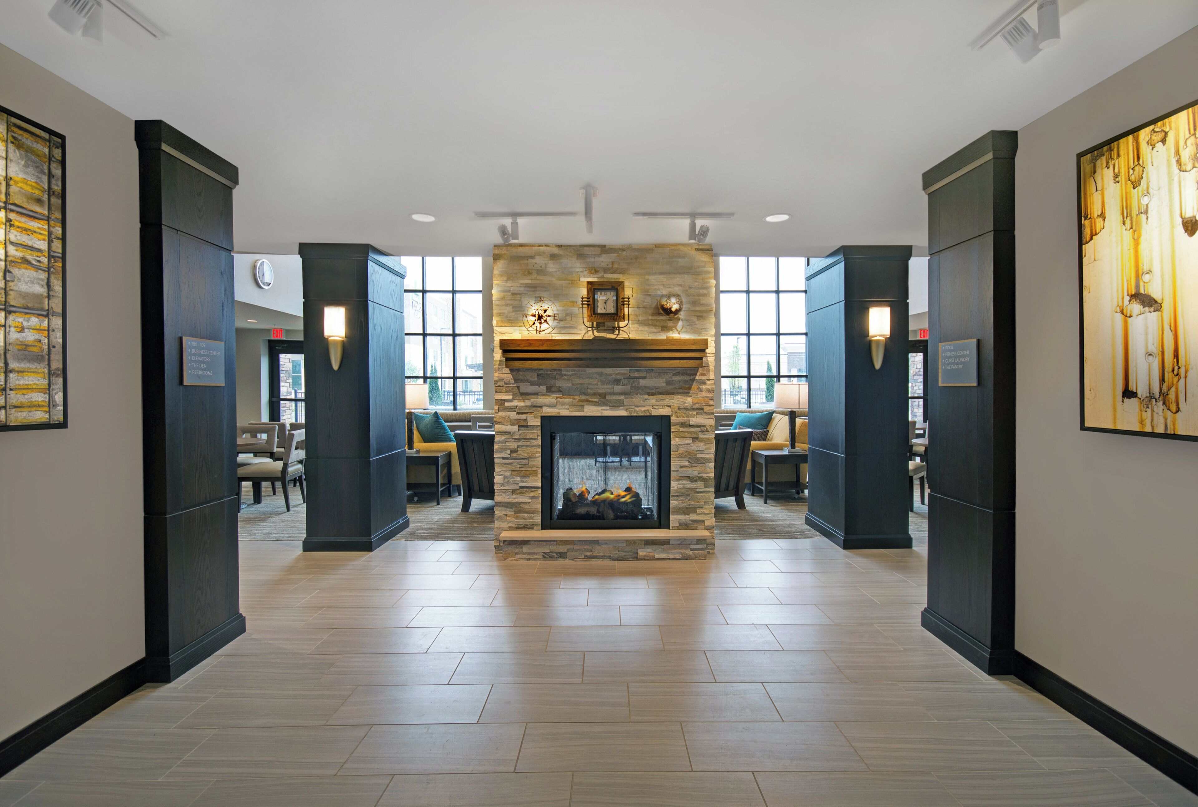 A hotel lobby with a stone fireplace, seating area, and large windows.