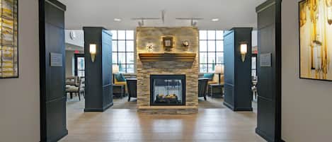 A hotel lobby with a stone fireplace, seating area, and large windows.