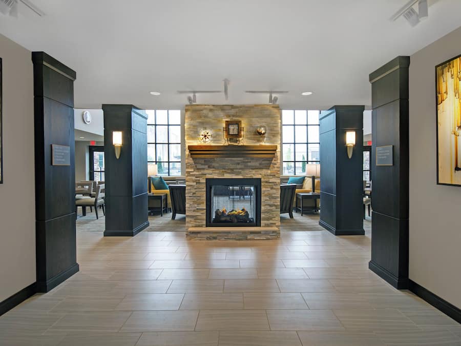 A hotel lobby with a stone fireplace, seating area, and large windows.