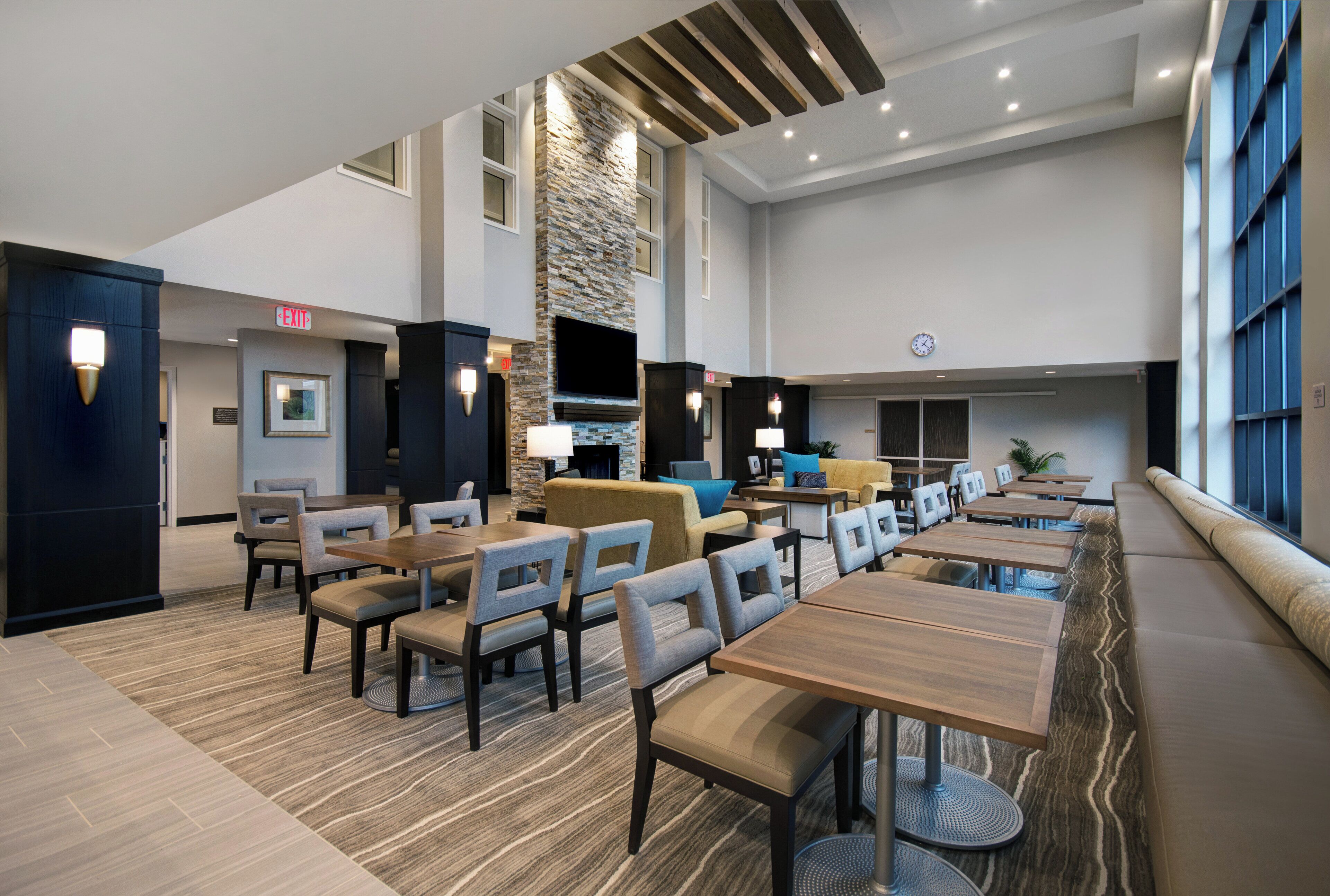 A hotel lobby with a seating area, tables, and a fireplace.