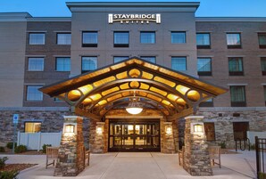 Entrada de un hotel Staybridge Suites con fachada de piedra, un acceso cubierto y un diseño moderno.