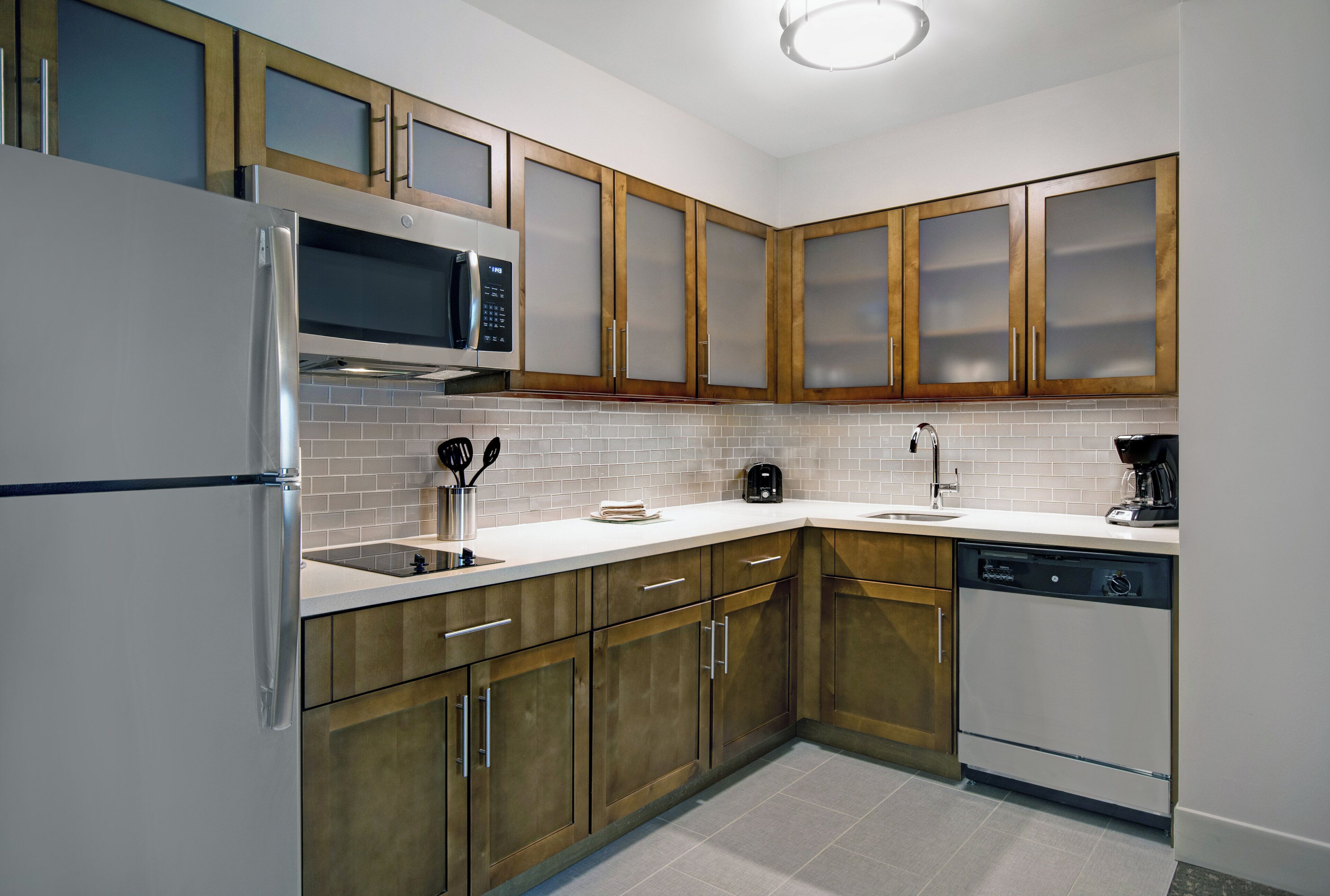 A modern kitchen with stainless steel appliances, wooden cabinets, and a tiled backsplash.