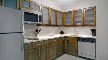 A modern kitchen with stainless steel appliances, wooden cabinets, and a tiled backsplash.