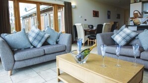 A modern living room with two grey sofas, a wooden coffee table, and a glass of champagne.