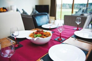 A dining table set with plates, glasses, and a bowl of pasta.