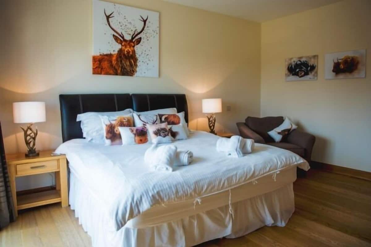 A hotel room with a large bed, two bedside tables, a nightstand, and a sofa.