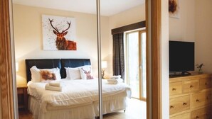 A bedroom with a large bed, a television, a dresser, and a deer artwork on the wall.